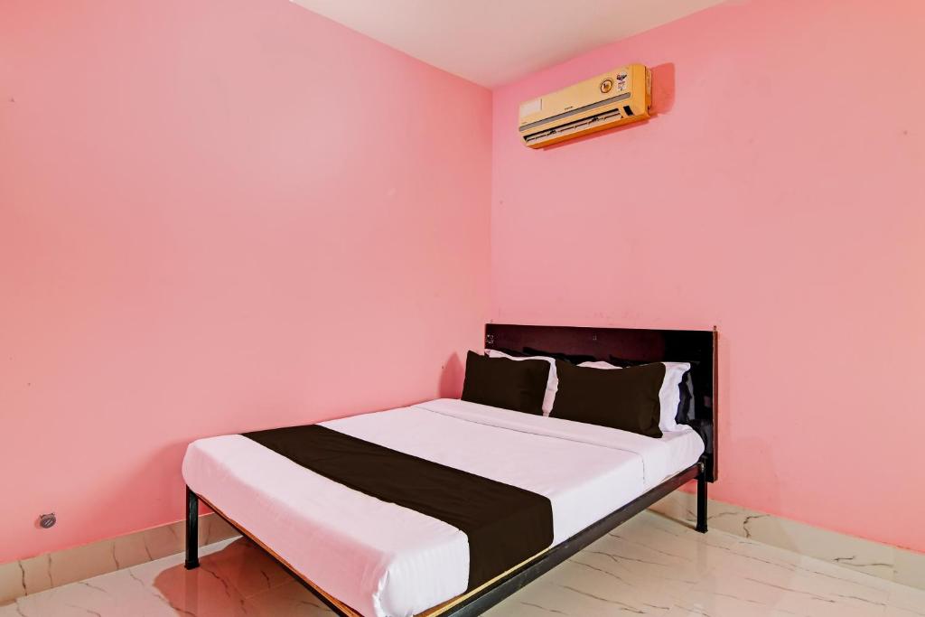 a bed in a room with a pink wall at OYO MAA BHUASUNI RESIDENCY in Cuttack