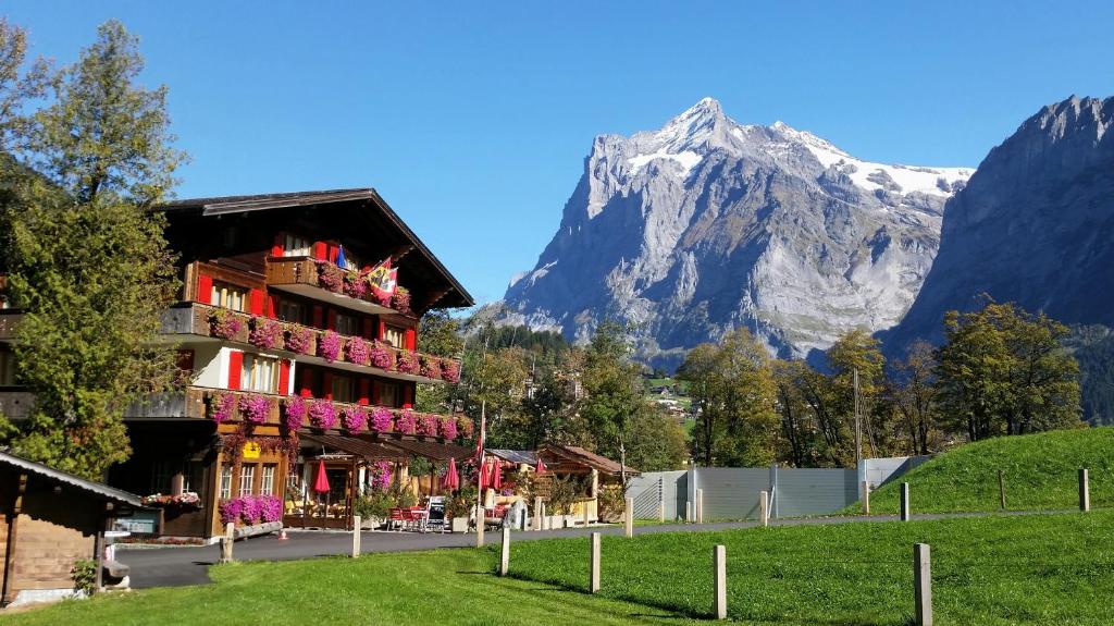 a building with flowers in front of a mountain at Chalet Bodenwald in Grindelwald