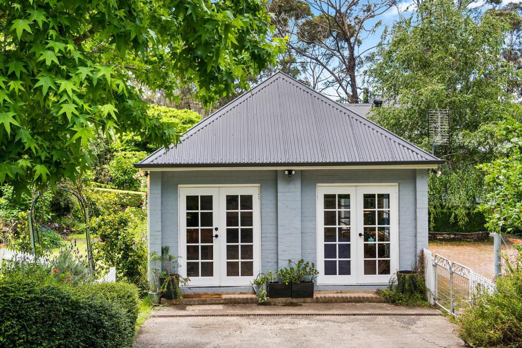 uma pequena casa azul com um telhado cinzento em Lush and Charming Country Escape, Stunning Gardens em Colo Vale