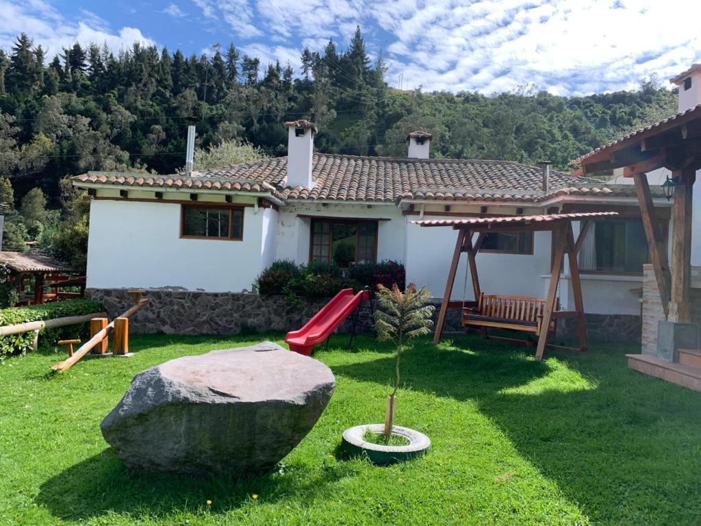 ein Haus mit einer roten Rutsche und einem Felsen im Hof in der Unterkunft Hacienda la campiña in Quito