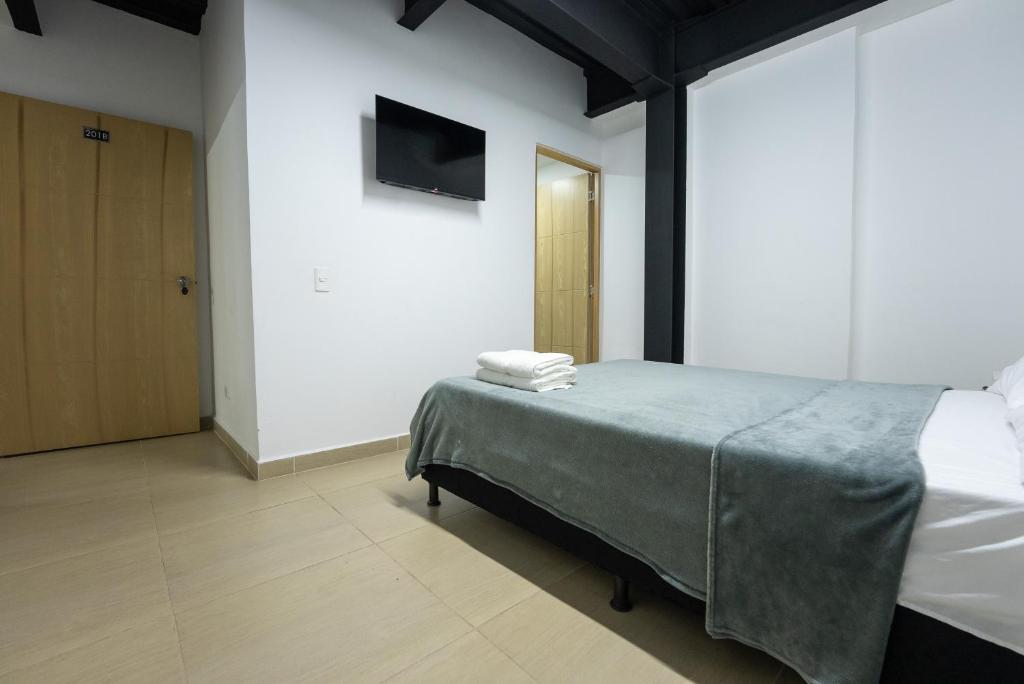 a bedroom with a bed and a tv on a wall at Coliving Tonchala in Medellín