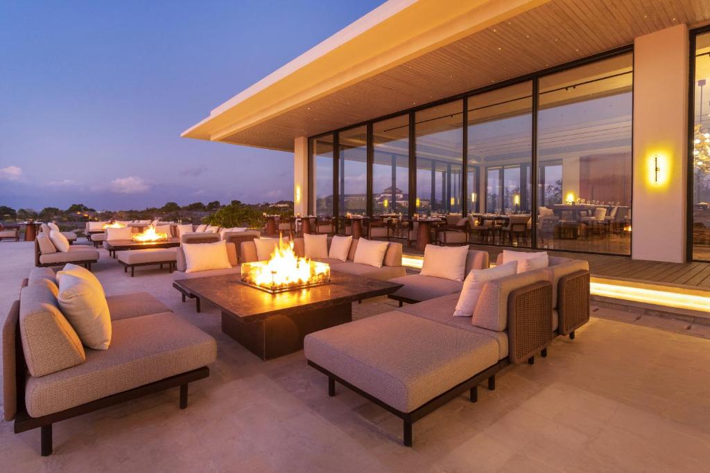 a patio with couches and tables and windows at Jumeirah Bali in Uluwatu