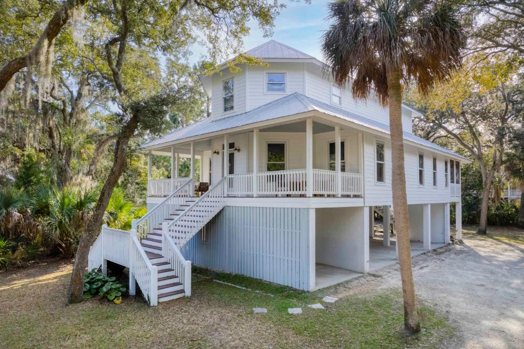 Casa blanca con porche y escalera en Chasing Waves Luxury Edisto Home 3 mins to Beach en Edisto Island