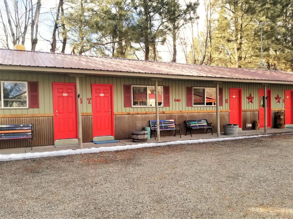 un bâtiment avec des portes rouges et des bancs à l'avant dans l'établissement Outpost Motel on the River, à Dolores