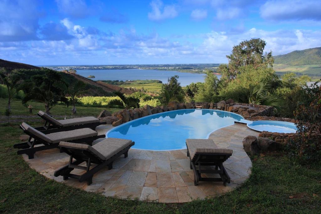 a swimming pool with benches and a view of a lake at La Hacienda Mauritius in Mahébourg