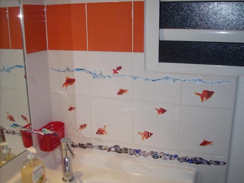 a bathroom with a sink with fish on the wall at Princess des Iles in Sainte-Anne