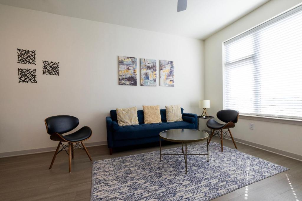 a living room with a blue couch and two chairs at Stunning Nulu 1BR CozySuites 05 in Louisville