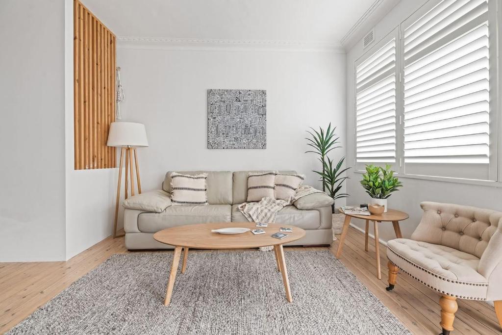 ein Wohnzimmer mit Sofa und Tisch in der Unterkunft Coastal Corner - Contemporary Chic by the Beach in Sydney