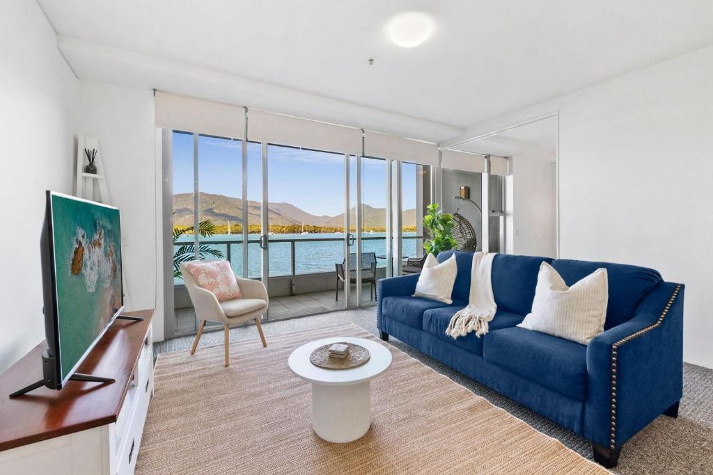 un salon avec un canapé bleu et une télévision dans l'établissement Lux Waterfront - prime location Pool Gym & Sauna, à Cairns