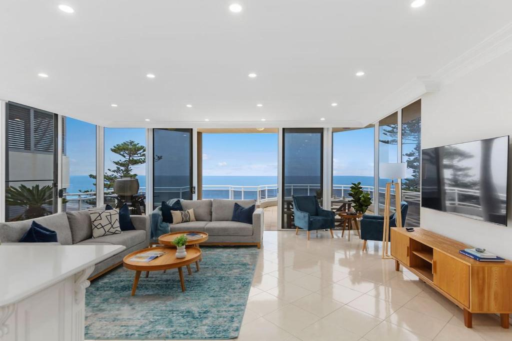 a living room with a couch and a table at Ocean Vista Escape - A Lofty Beachfront Penthouse in Wollongong
