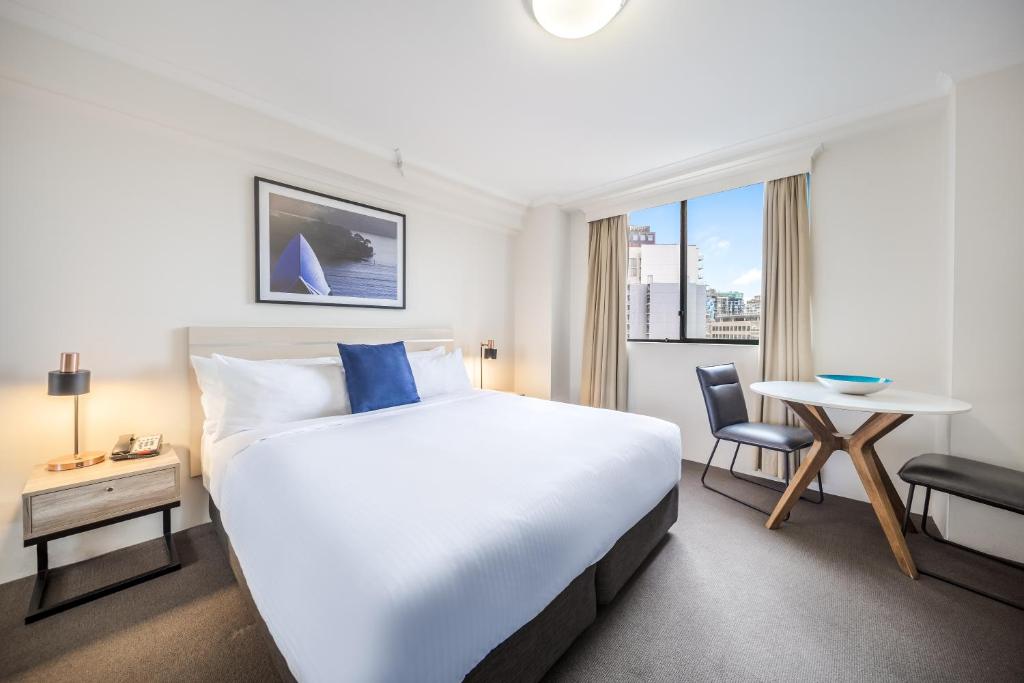 悉尼Oaks Sydney Castlereagh Suites的一间配有大床和桌子的酒店房间