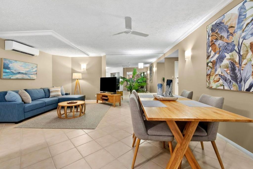 sala de estar con mesa y sofá azul en Reef Apartment Cairns en Edge Hill