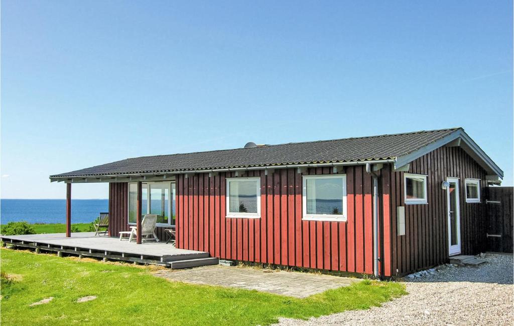 una pequeña casa roja con un patio y el océano en Awesome Home In Faaborg With Wifi, en Bøjden