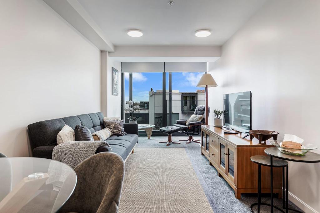 a living room with a couch and a tv at Zodiak Stays Cozy CBD 2BR Near Top Dining Spots in Auckland