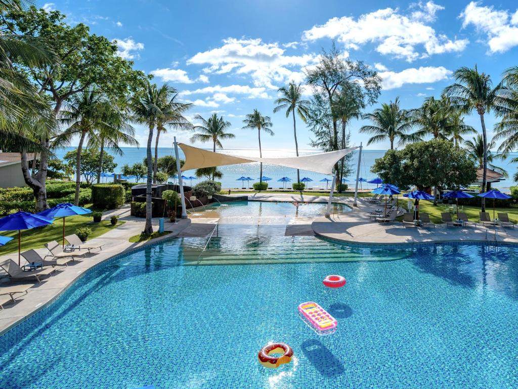 - une piscine avec des chaises et des parasols dans un complexe dans l'établissement OZO Chaweng Samui, à Chaweng