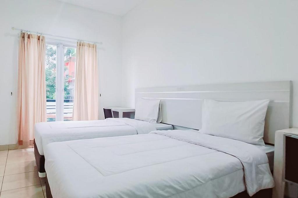 2 białe łóżka w pokoju z oknem w obiekcie Gading Serpong Hotel Near Stadion Persita Redpartner w mieście Anggris