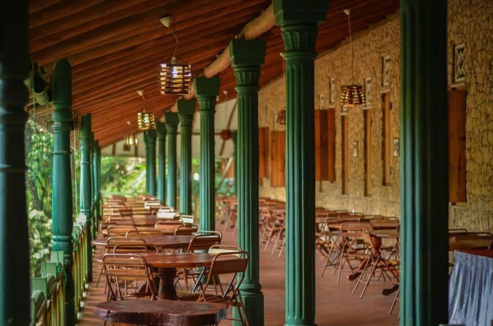 a row of tables and chairs in a room with green columns at Belihuloya Terico Resort in Balangoda