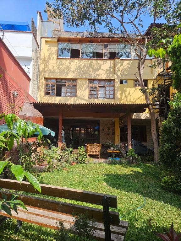 a building with a bench in front of a yard at Garden House Miraflores in Lima