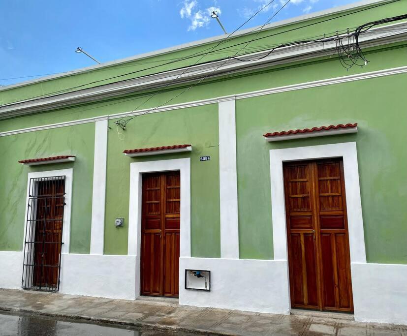 a green building with three wooden doors on it at Casa Iktal Luxury - Centro Mérida in Mérida