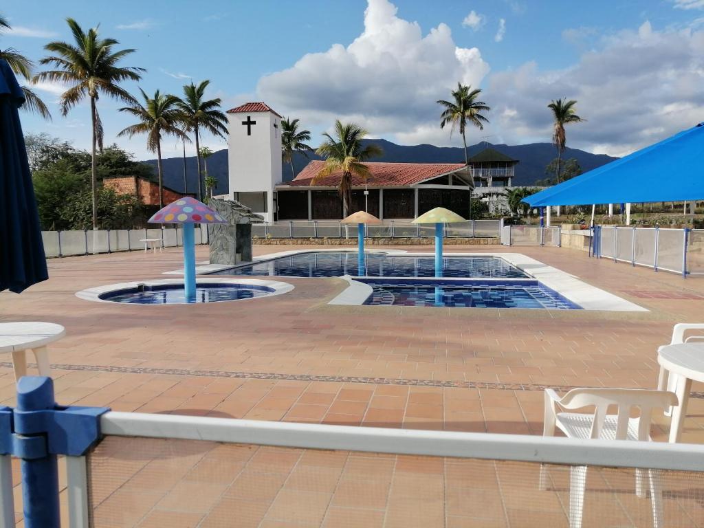 una piscina con sombrillas, mesas y palmeras en APARTAMENTO CAMPESTRE CHINAUTA, en La Serena