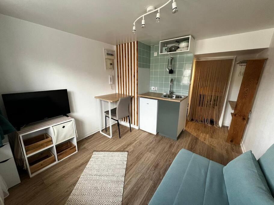 pequeña sala de estar con TV y cocina en Studio proche du centre-ville, en Arpajon