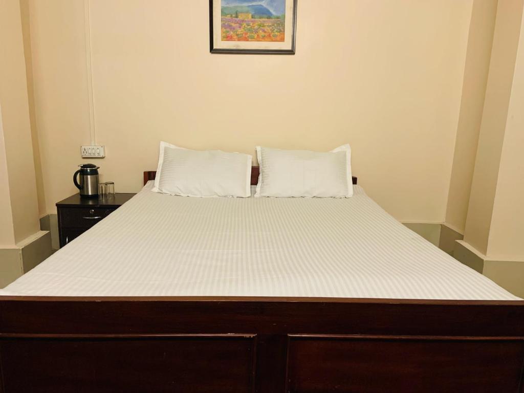 een bed met twee kussens in een kamer bij OYO Flagship Hotel West End in Darjeeling