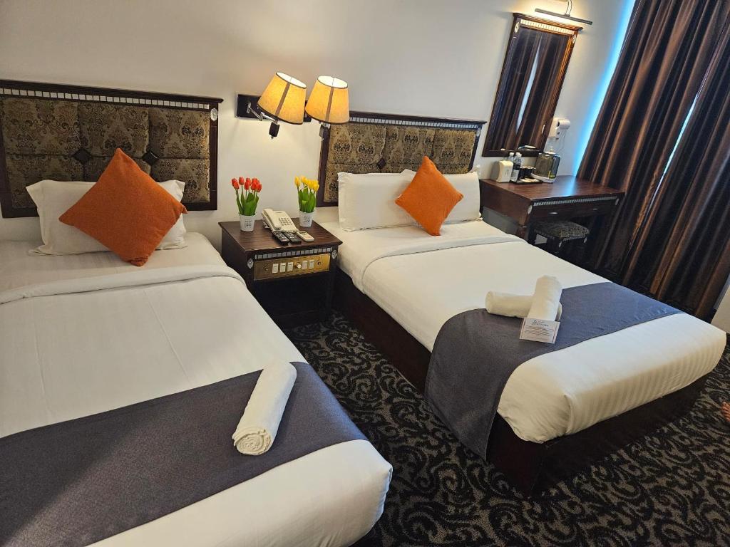 a hotel room with two beds with orange pillows at Go Lodge Hotel Kuantan in Kuantan