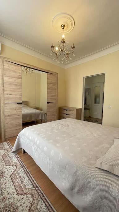 Un dormitorio con una gran cama blanca y una lámpara de araña. en Salamat Apartments - Best location 8, en Bishkek