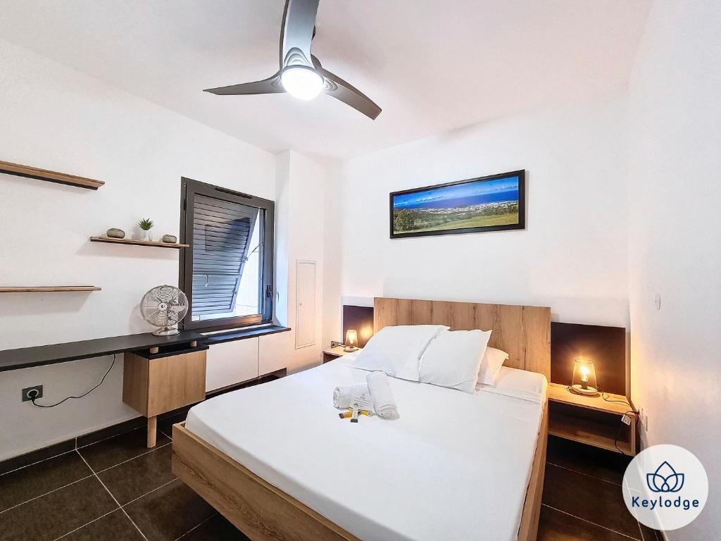 a bedroom with a white bed and a window at Escale Créole - T2 à 10 minutes de l'aéroport - Sainte Clotilde in Saint-Denis