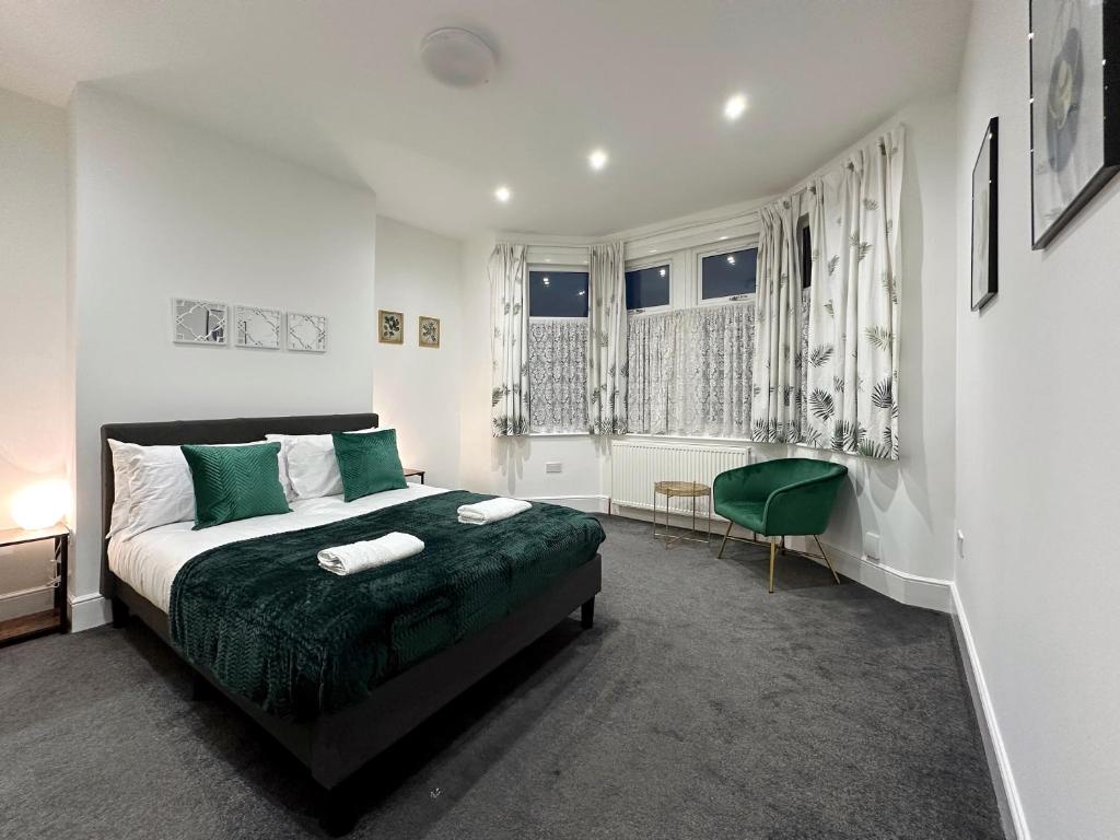 a bedroom with a bed with green sheets and a chair at Ana’s Place in Harrow on the Hill in Harrow