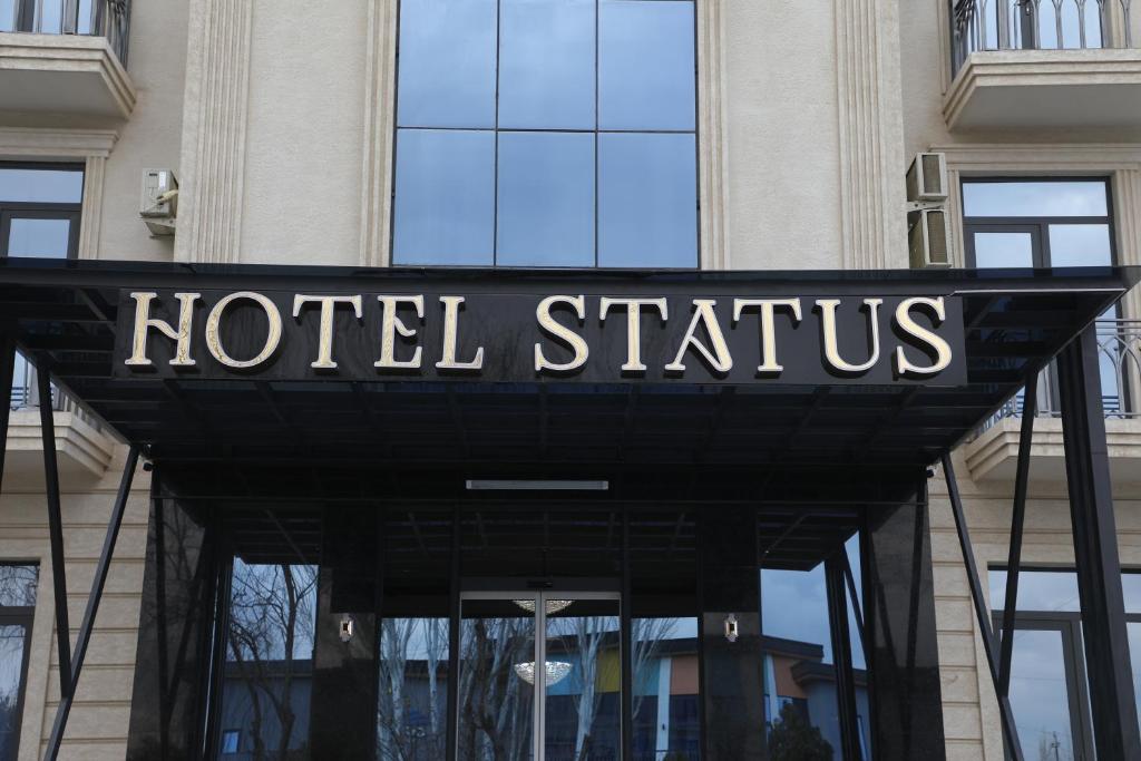 una señal de hotel en la parte delantera de un edificio en Status Hotel, en Qarshi