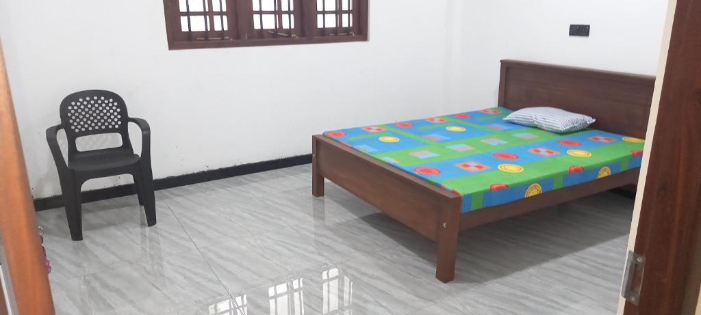 a bed and a chair in a room at Family Villa Thalpavila in Ambatenna