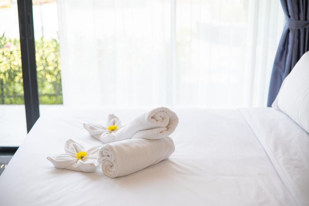 a pile of towels on a bed with flowers at SeeView Resort (ซีวิว รีสอร์ต) in Ban Pak Nam