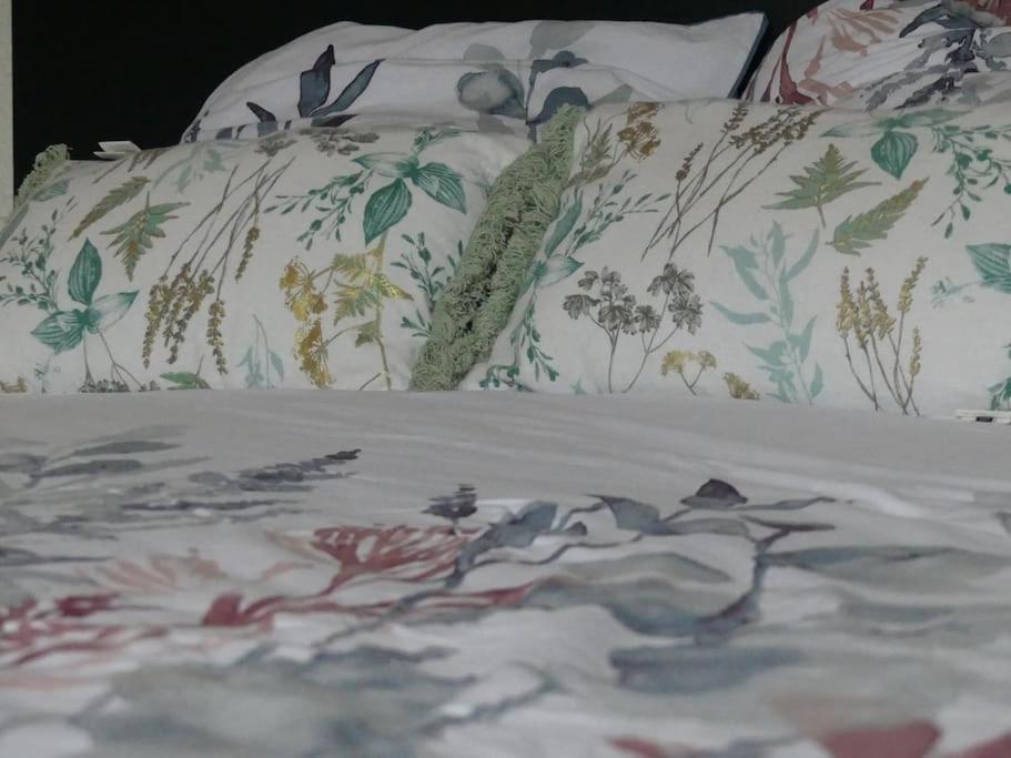 - un lit avec des draps floraux et des oreillers dans l'établissement Bel Appart' Confort VILLEURBANNE TRAM T3 WIFI, à Villeurbanne