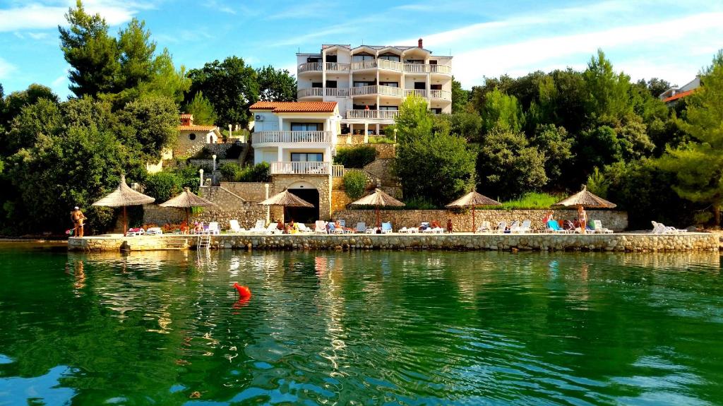 una piscina de agua con un hotel en el fondo en Hotel Lucija en Posedarje