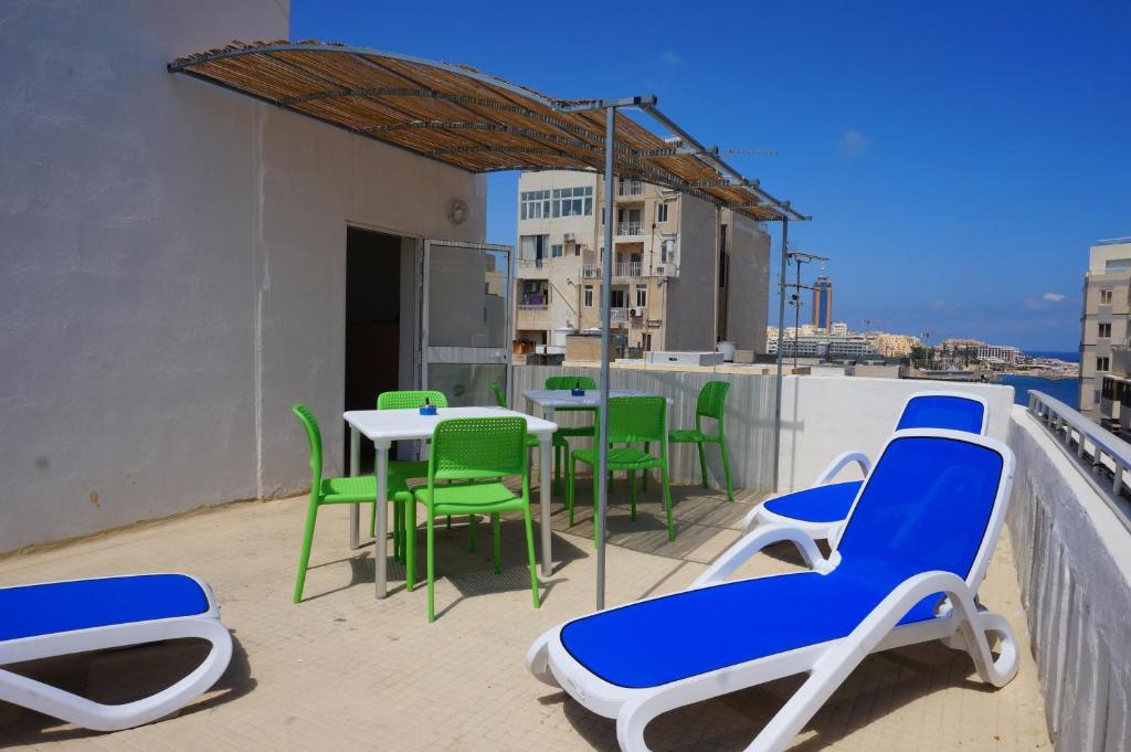 eine Terrasse mit Stühlen und Tischen auf dem Balkon in der Unterkunft Hostel 94 in Sliema