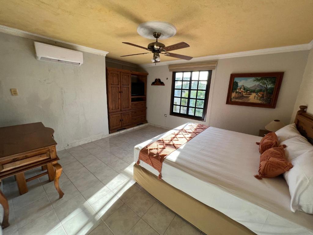 a bedroom with a large bed with a ceiling fan at Hotel Casablanca 160 in Mérida