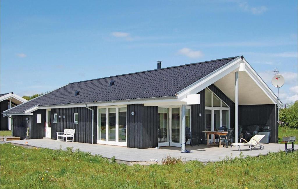 Spodsbjergにある4 Bedroom Beautiful Home In Rudkbingのパティオ、テーブル、椅子が備わるブラックハウスです。