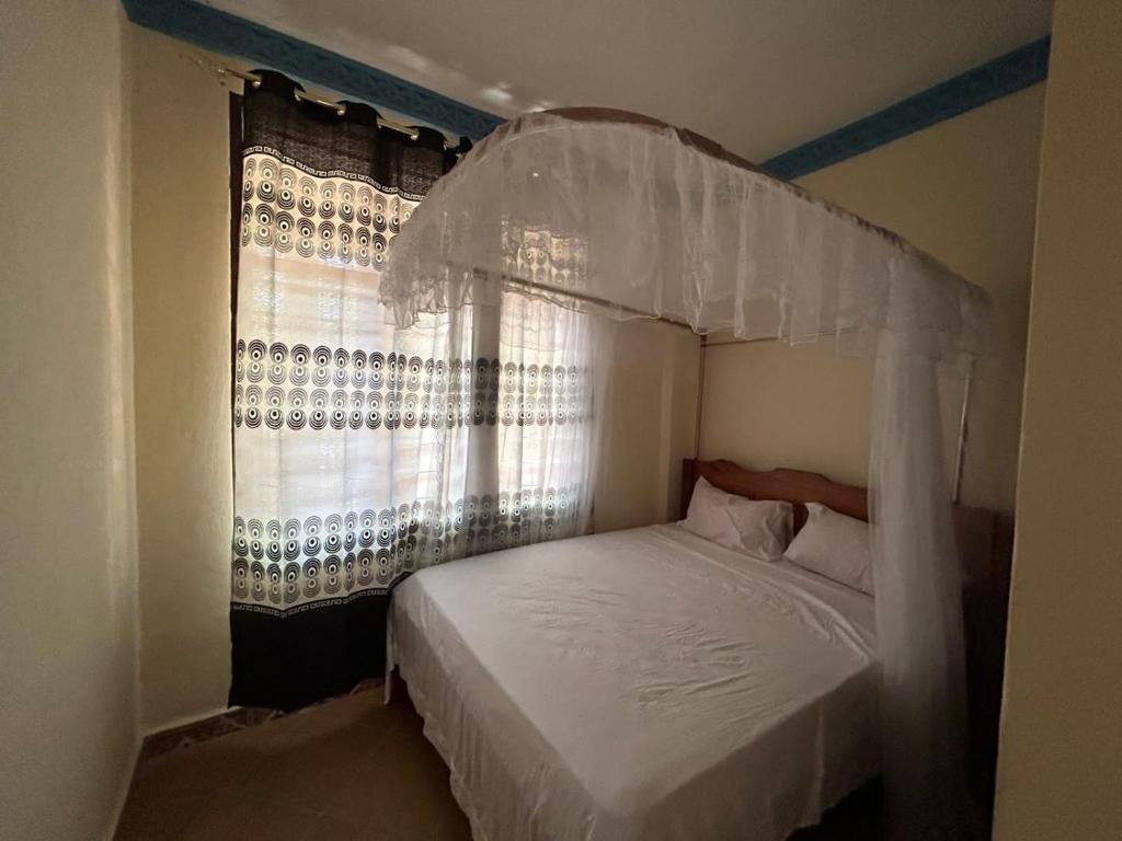 sypialnia z łóżkiem z baldachimem i oknem w obiekcie Julia Top Holiday Home w mieście Diani Beach