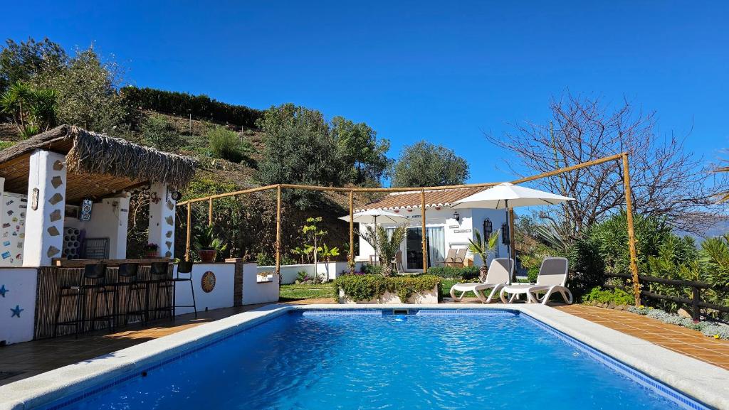 een zwembad met twee stoelen en een huis bij Casita Johanna in Viñuela
