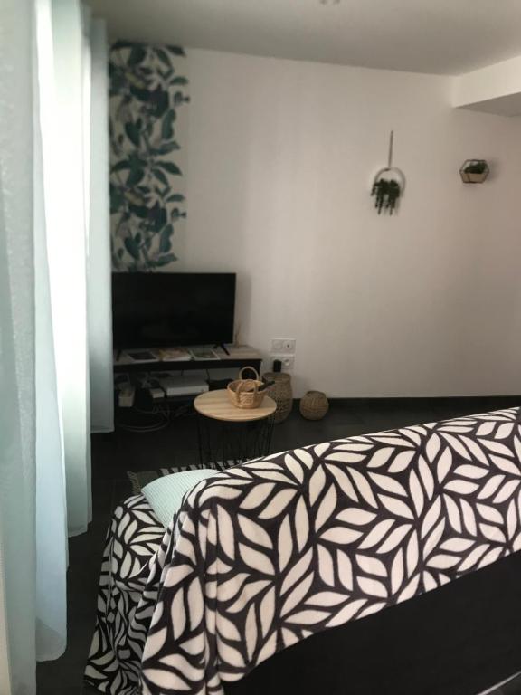 une chambre avec un lit et une table avec une télévision dans l'établissement Petite maison, à Carcassonne