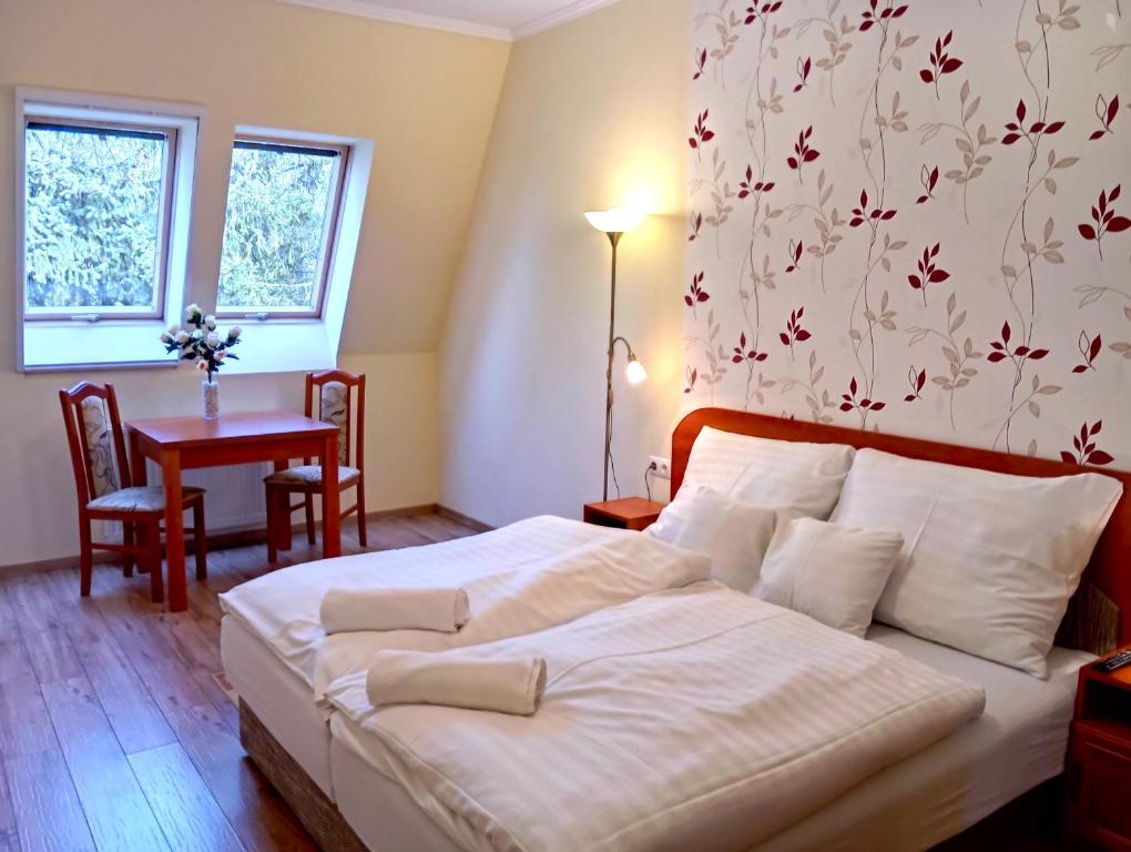 a bedroom with a bed and a table and windows at Patak-Party Apartmanok in Bogács
