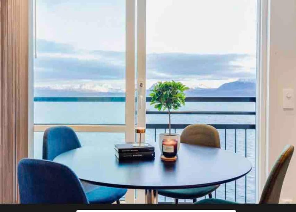 a table and chairs in front of a large window at Nydelig leilighet med sjøutsikt sentralt i byen in Harstad