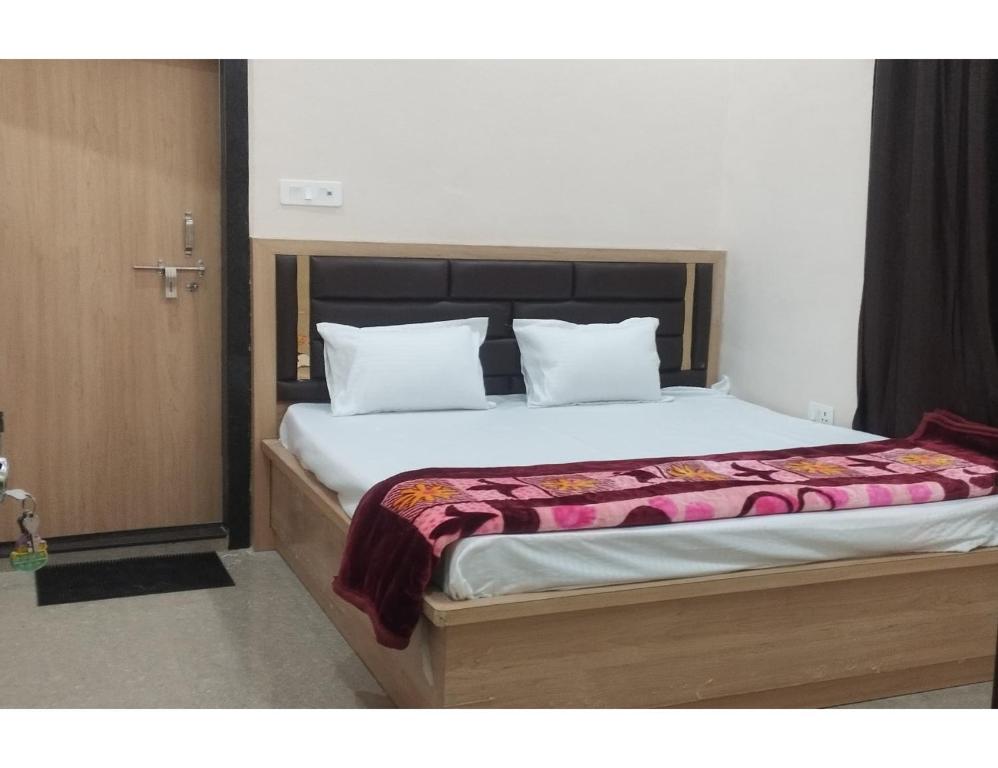 a bedroom with a large bed with a wooden headboard at Uma Hotel, Chitrakoot in Sītāpur Mūāfi
