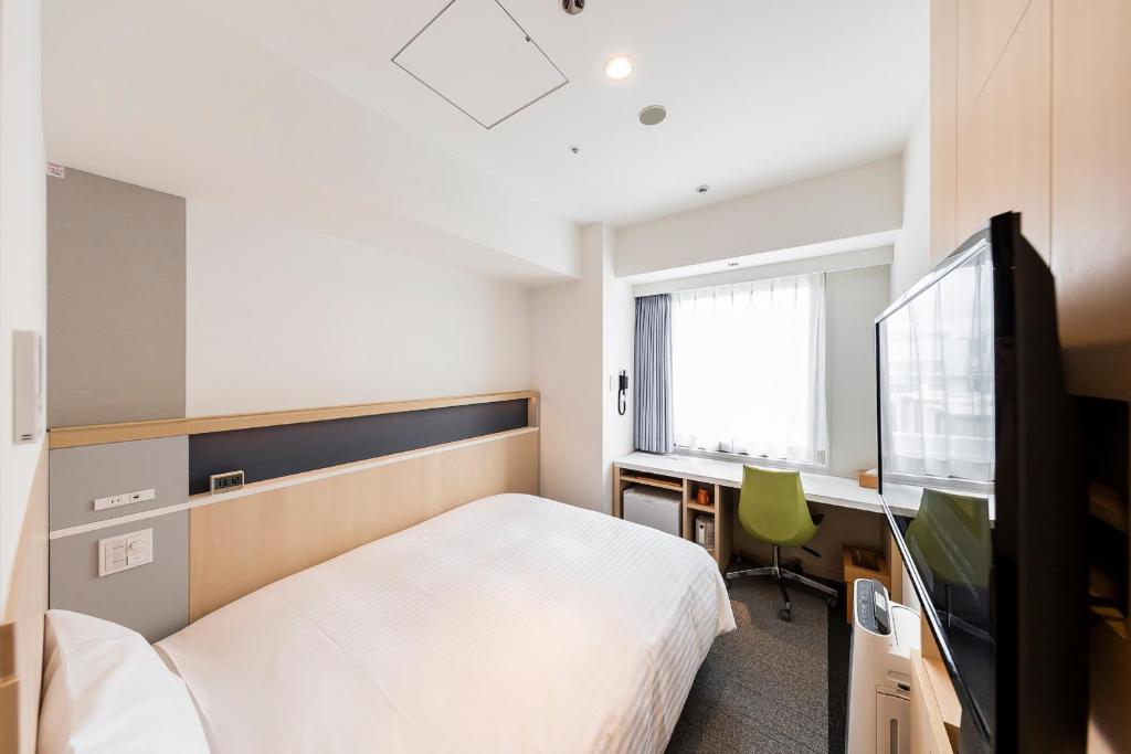 a bedroom with a bed and a desk and a tv at Via Inn Prime Shinsaibashi Yotsubashi in Osaka