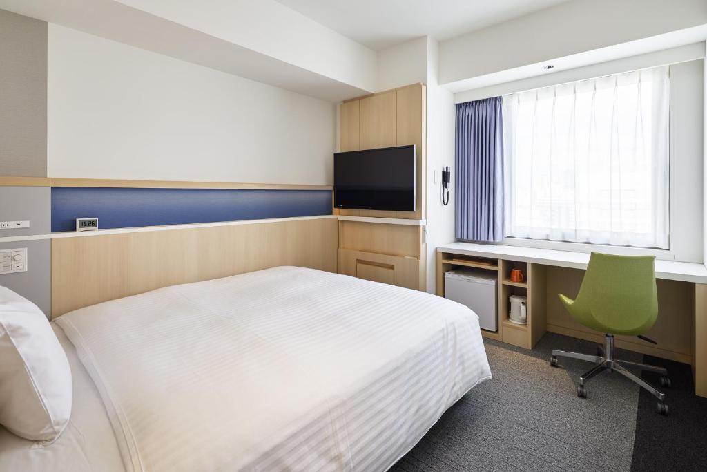 a bedroom with a bed and a desk and a television at Via Inn Prime Shinsaibashi Yotsubashi in Osaka