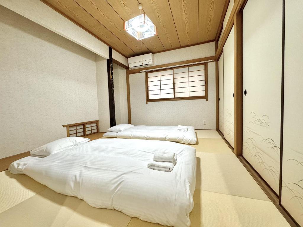 a bedroom with two beds in it with a window at 最大10名で泊まれる貸別荘日本橋駅徒歩5分黒門市場に隣接し道頓堀 难波 心斎橋徒歩圏内 in Osaka