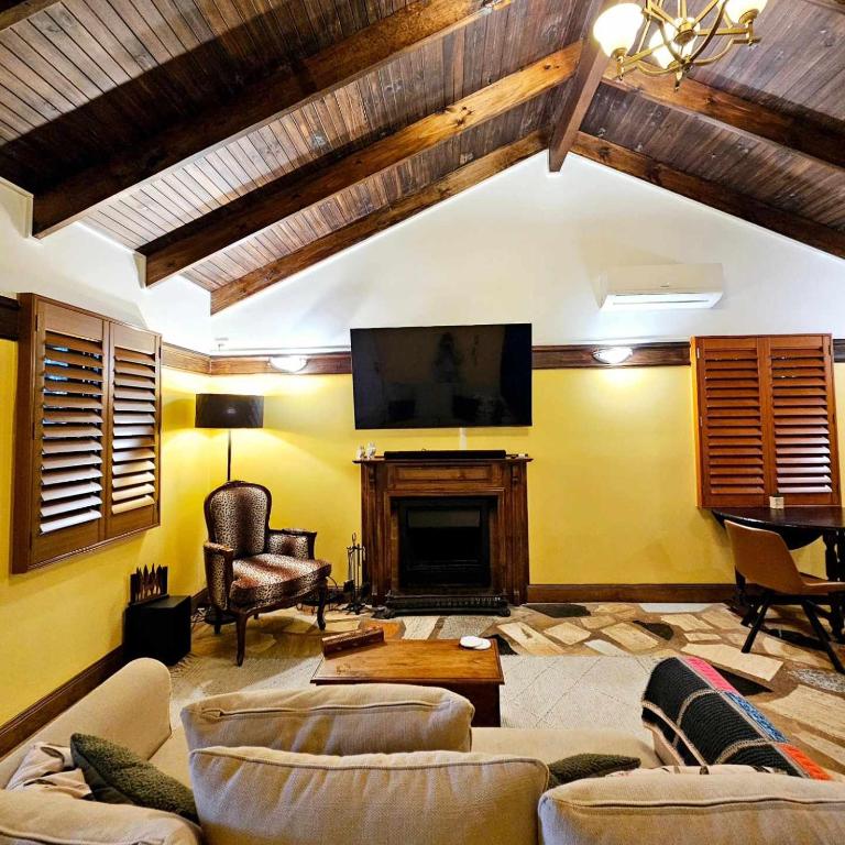 a living room with couches and a tv and a fireplace at The Gamekeepers Spa Cottage in Tamborine Mountain in Mount Tamborine