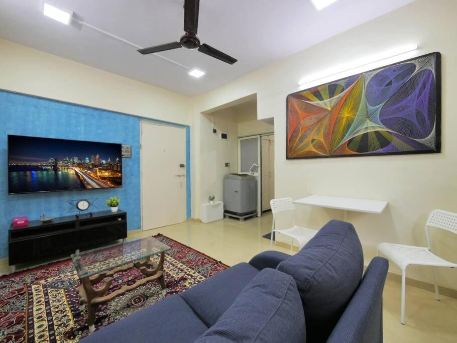 un salon avec un canapé bleu et une télévision dans l'établissement Solace - 1 BHK - Walk away from Carter road, à Mumbai