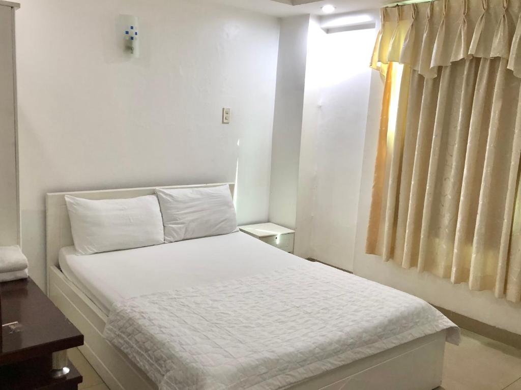 a bedroom with a bed with white sheets and a window at Seven Stars Hotel in Ho Chi Minh City